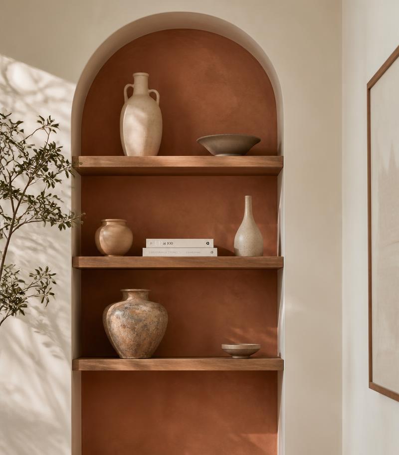Arched terracotta niche with wooden shelves and ceramics